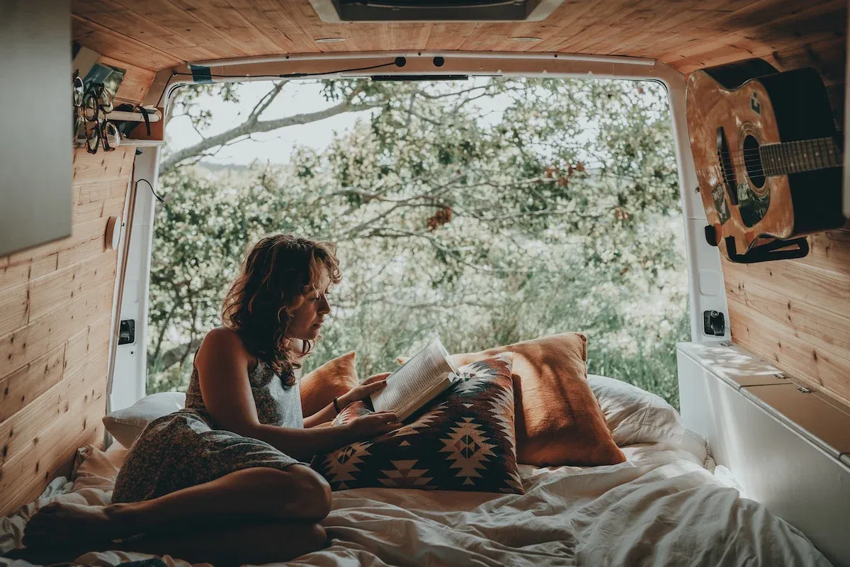 A woman reading on her bed in her van